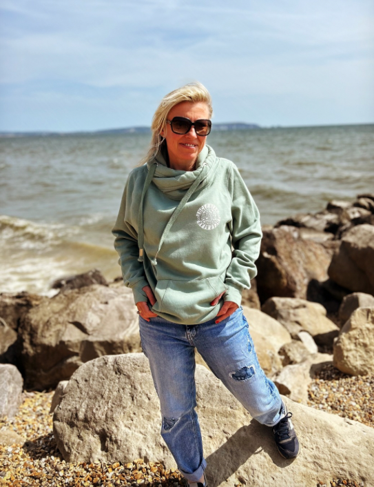 Woman on a beach wearing dusty green unisex Power Hoodie