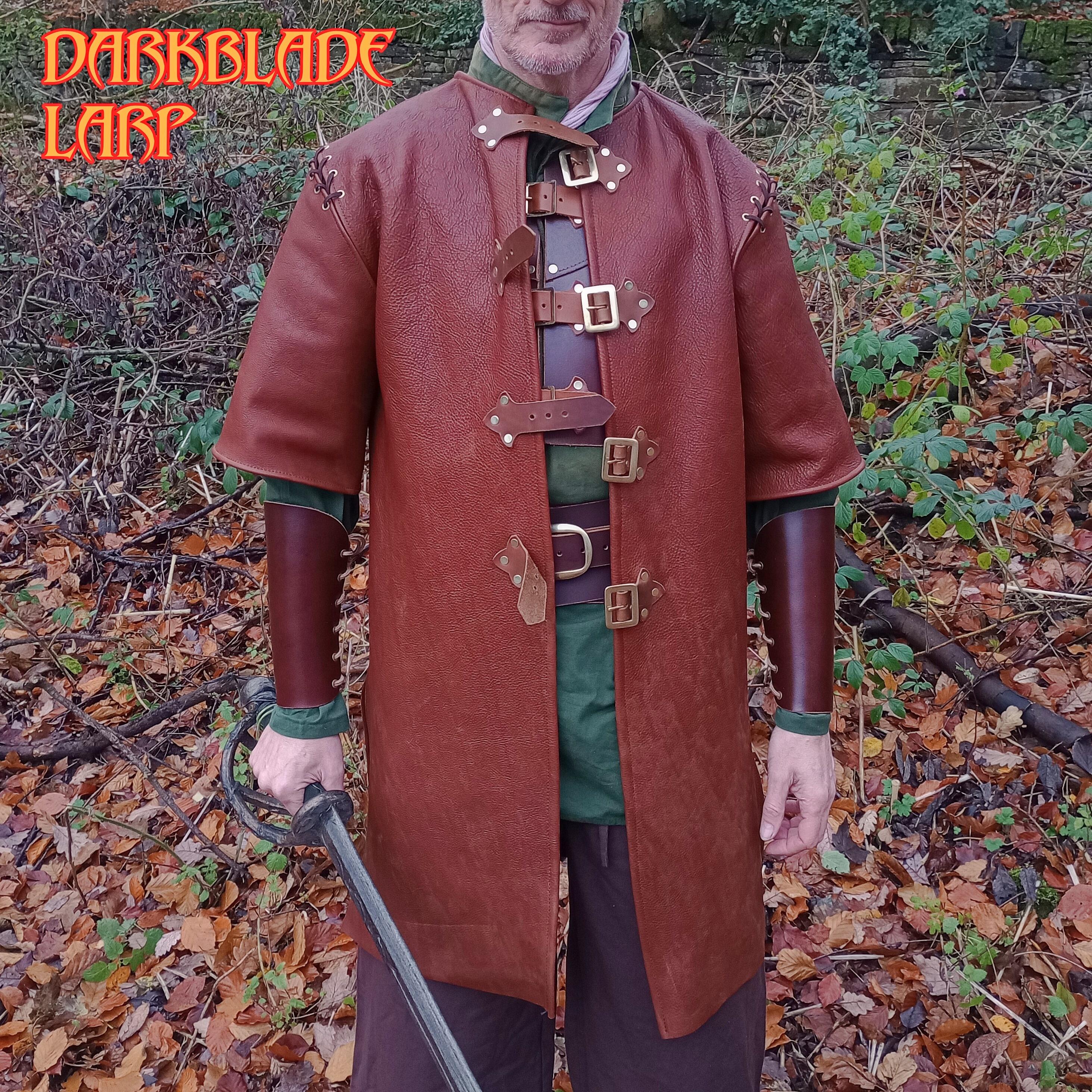 A figure wearing a knee length, short sleeved leather coat. The coat is open to show a short breastplate and a wide belt underneath. The figure is wearing brown leather vambraces and holds a sword.