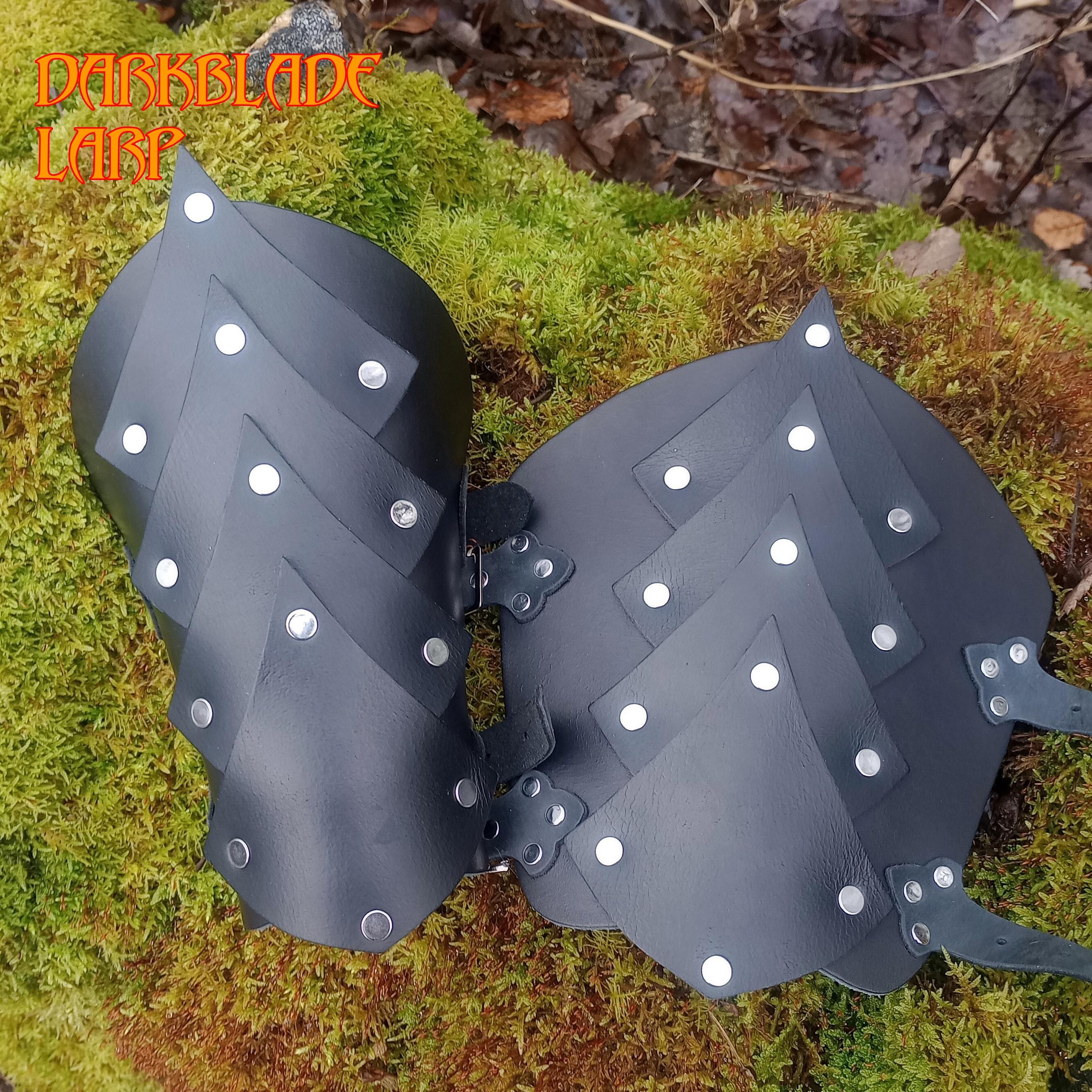 A pair of black vambraces with what looks like a line of scales going down the middle