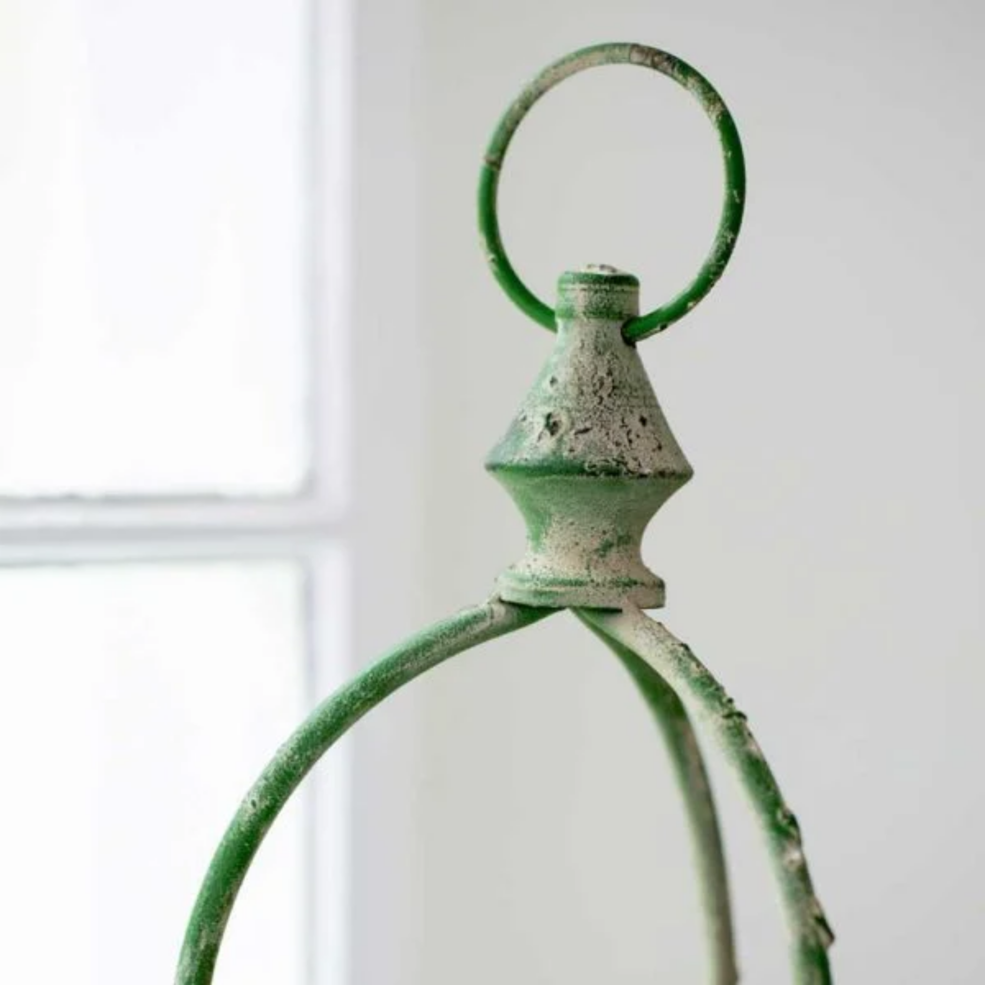 Close up vintage green metal hurricane lantern focusing on the hanging loop