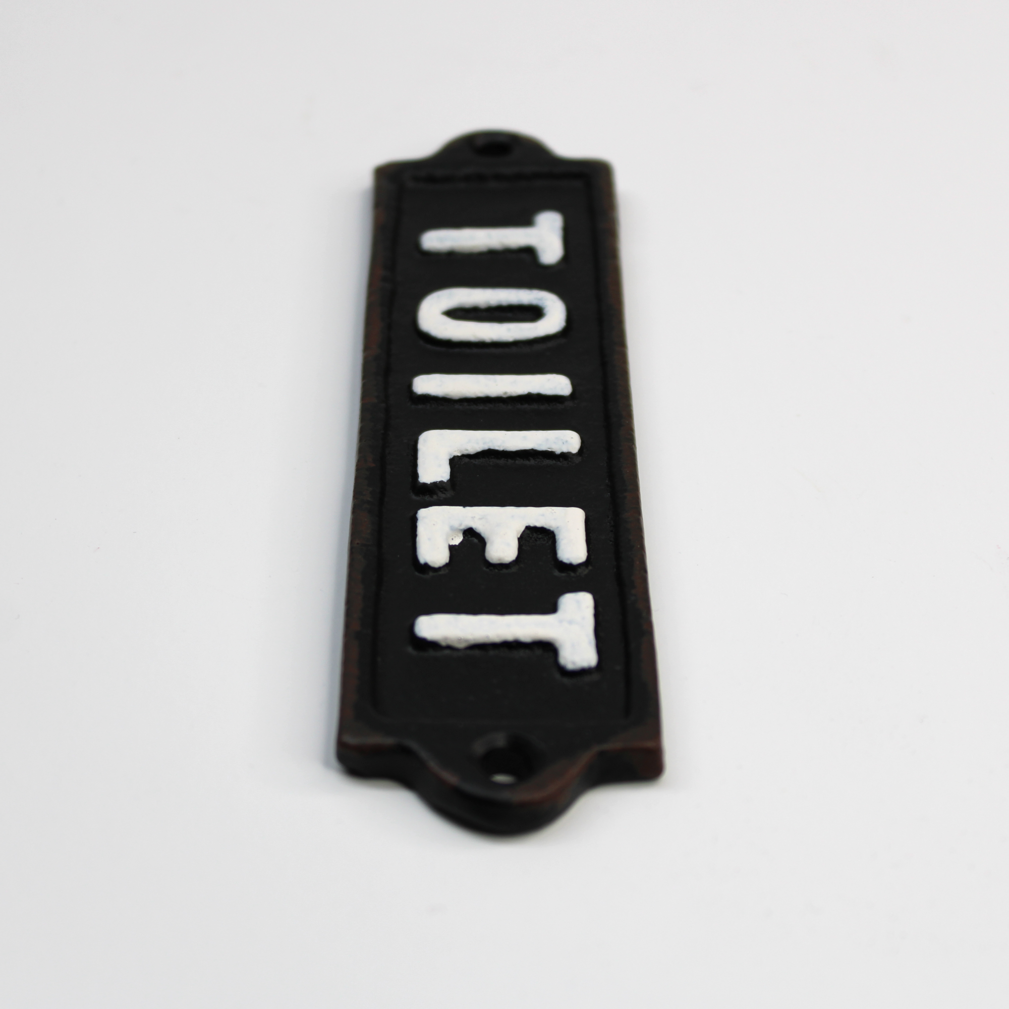 Wall-mounted metal sign that reads 'TOILET' in white raised letters against a dark cast iron plate.