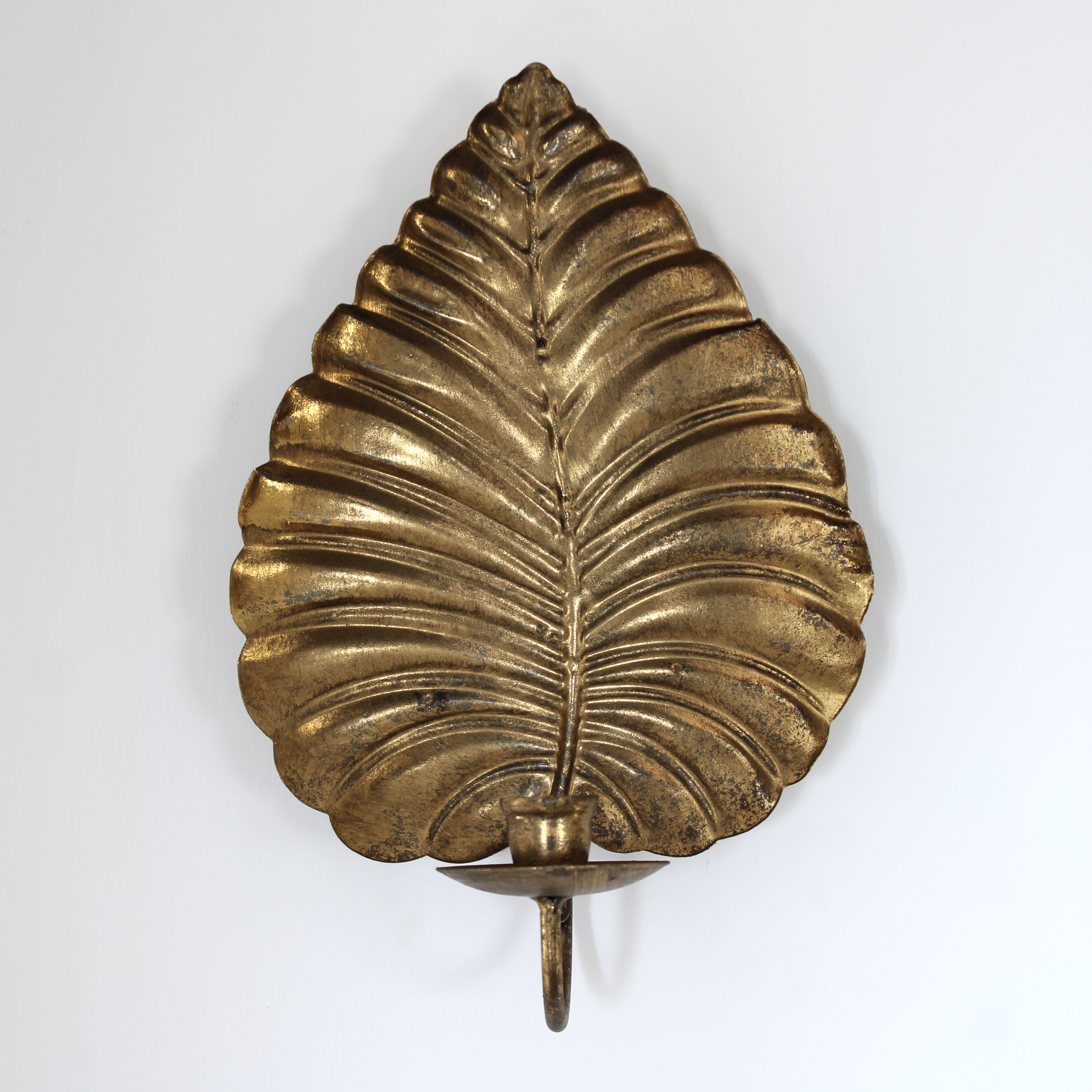 Decorative gold leaf wall sconce with single candle cup for home interior accent.