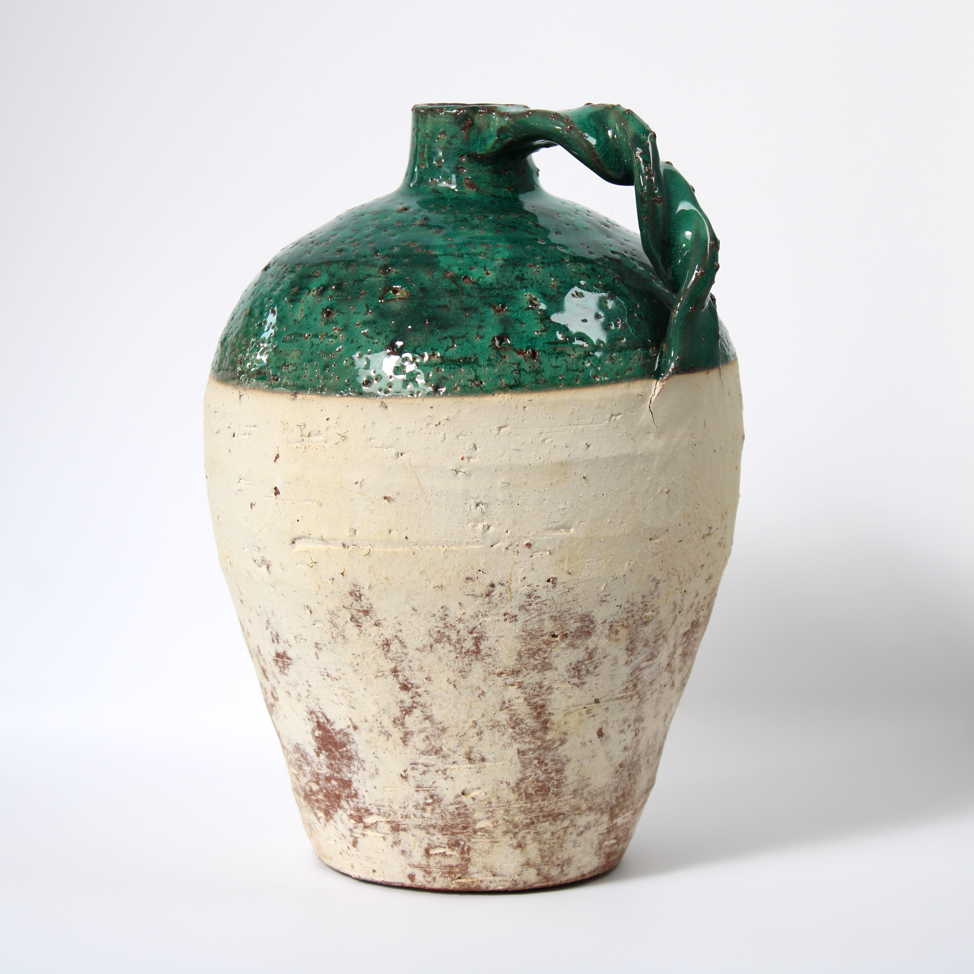 rustic terracotta jug with green glaze, back view.
