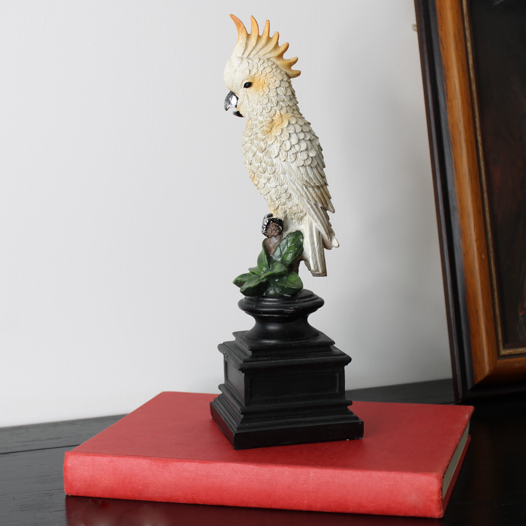 White cockatoo statue used as an accent on a bookshelf for Tropical Glam decor.