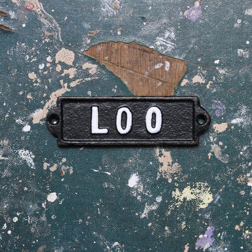 Metal loo door plate on a vintage table top