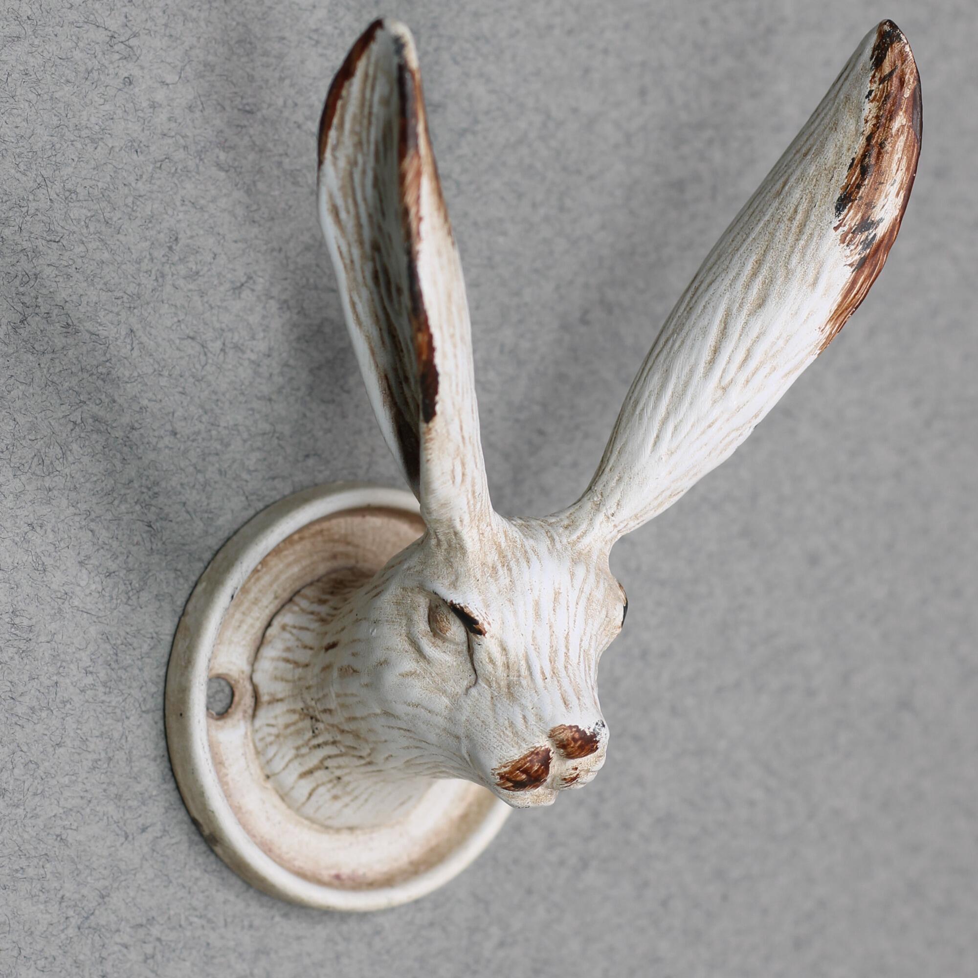 Close up of a metal rabbit wall hook with vintage white finish.