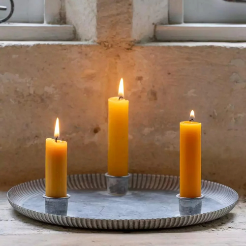Round fluted zinc candle tray with three yellow dinner candles
