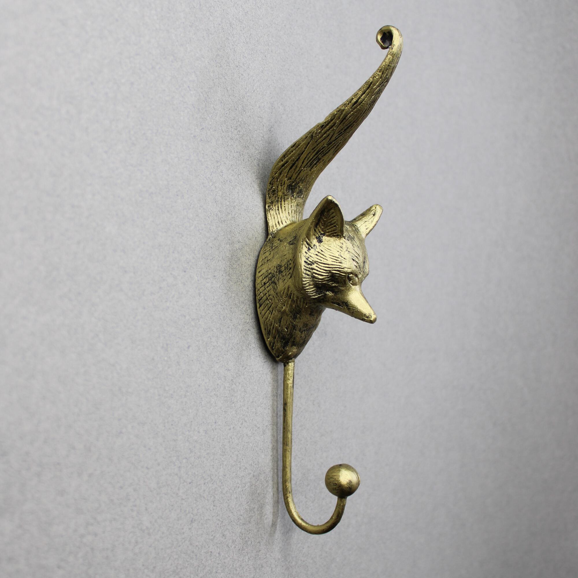 Antique gold fox head wall hook with detailed textured fur and an upward-curving tail.