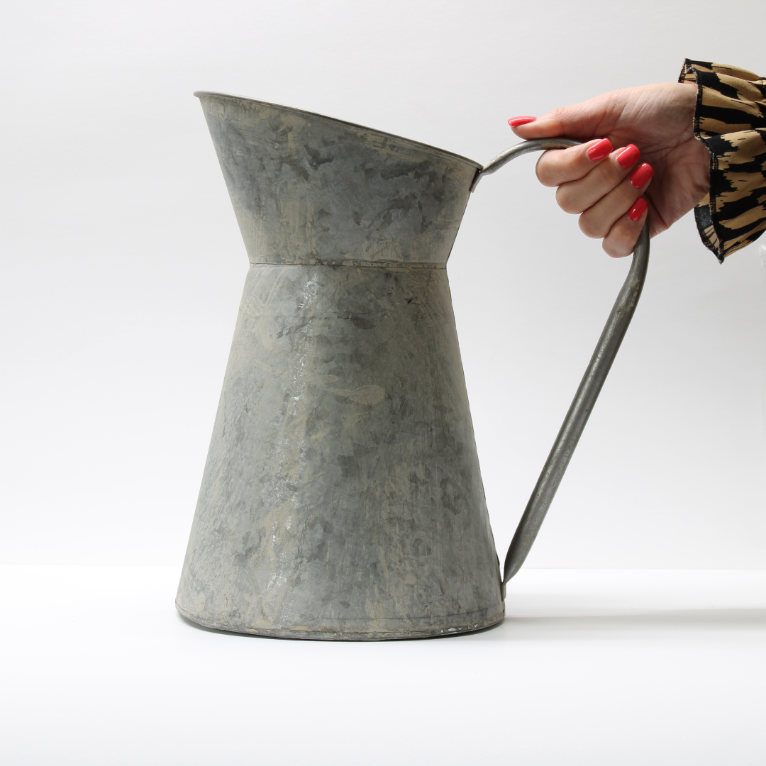 vintage style metal pitcher jug held by the handle
