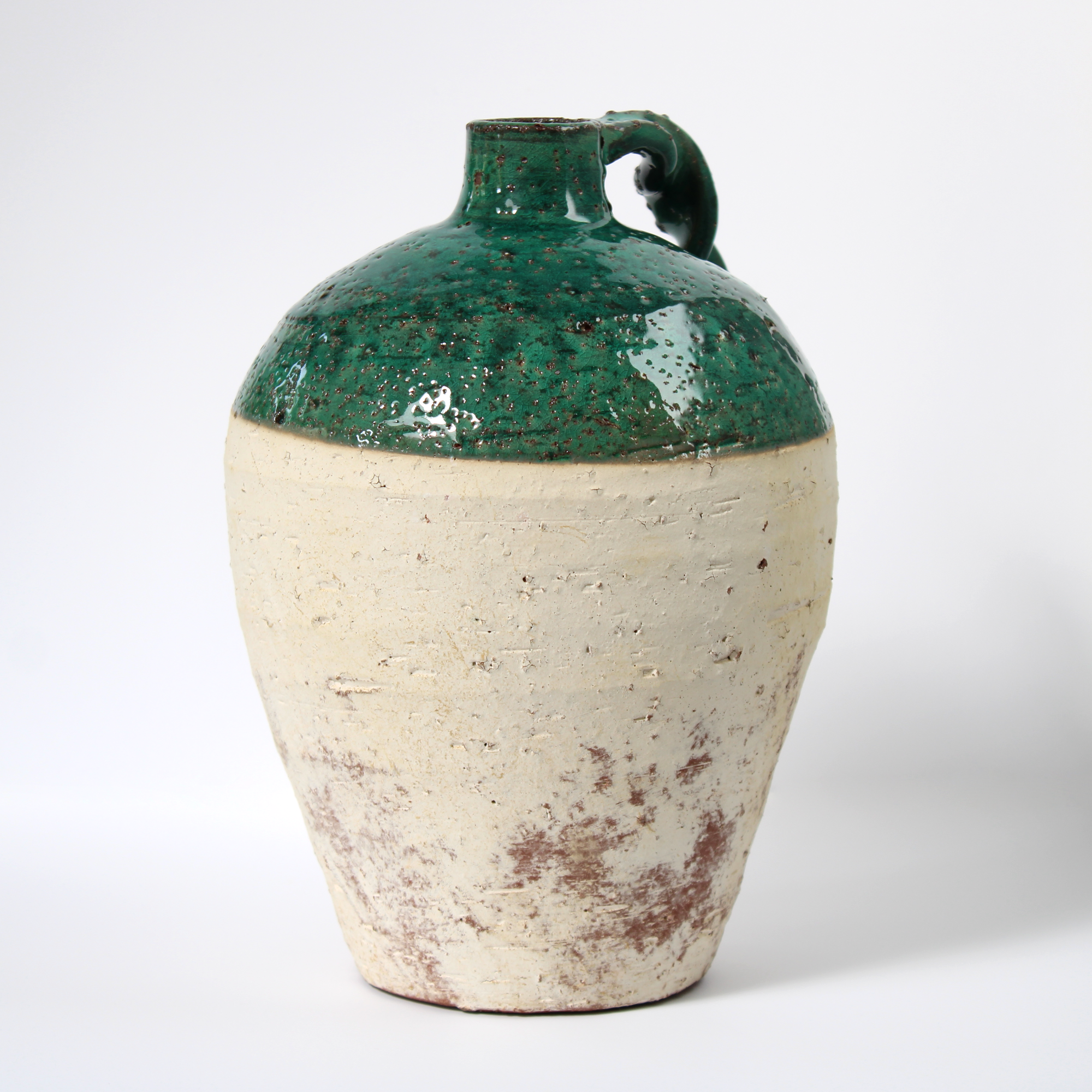rustic terracotta jug with green glaze, front view.