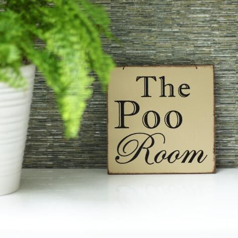 fun bathroom sign on the back of a toilet next to a green plant