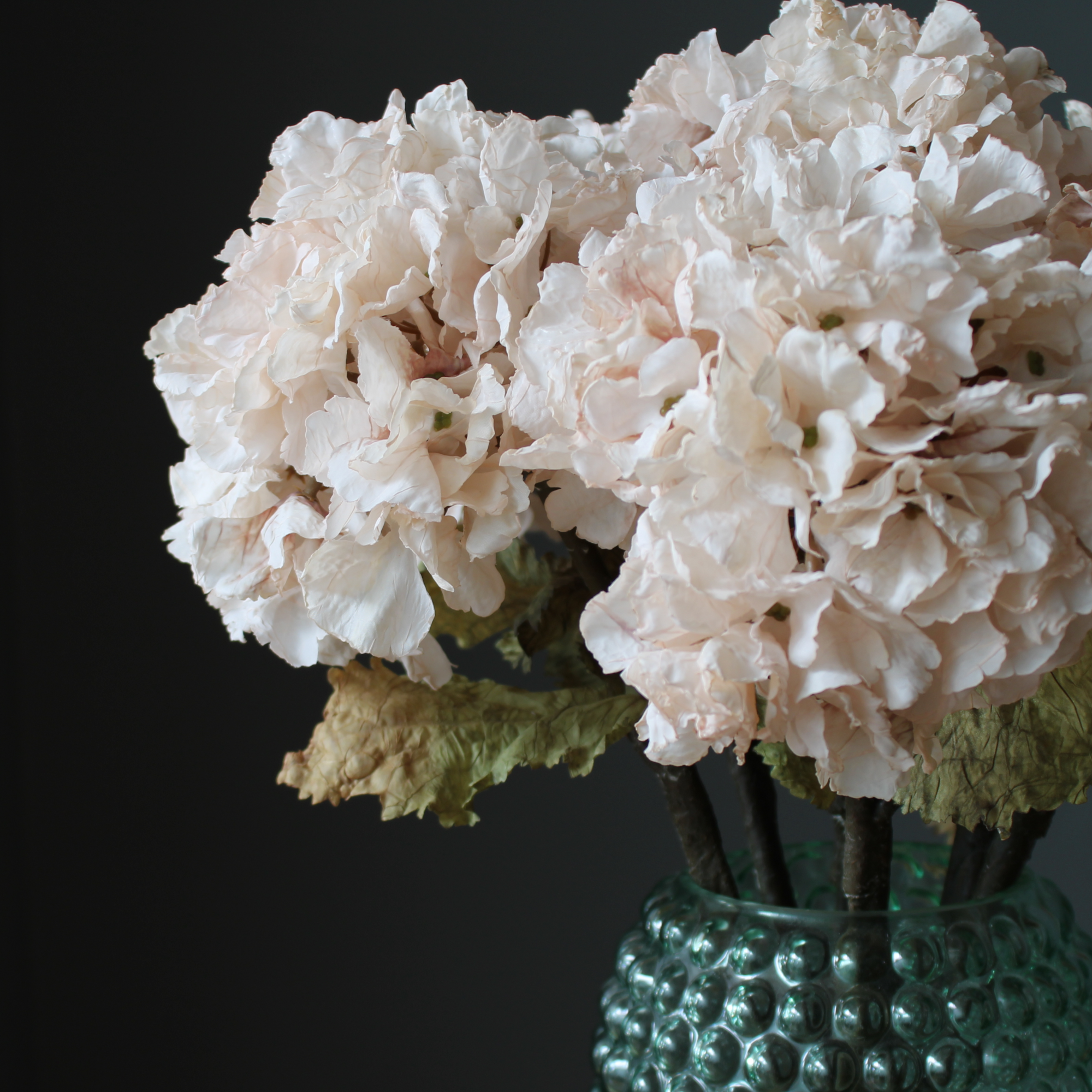 right side close up of a cream artificial hydrangea bouquet