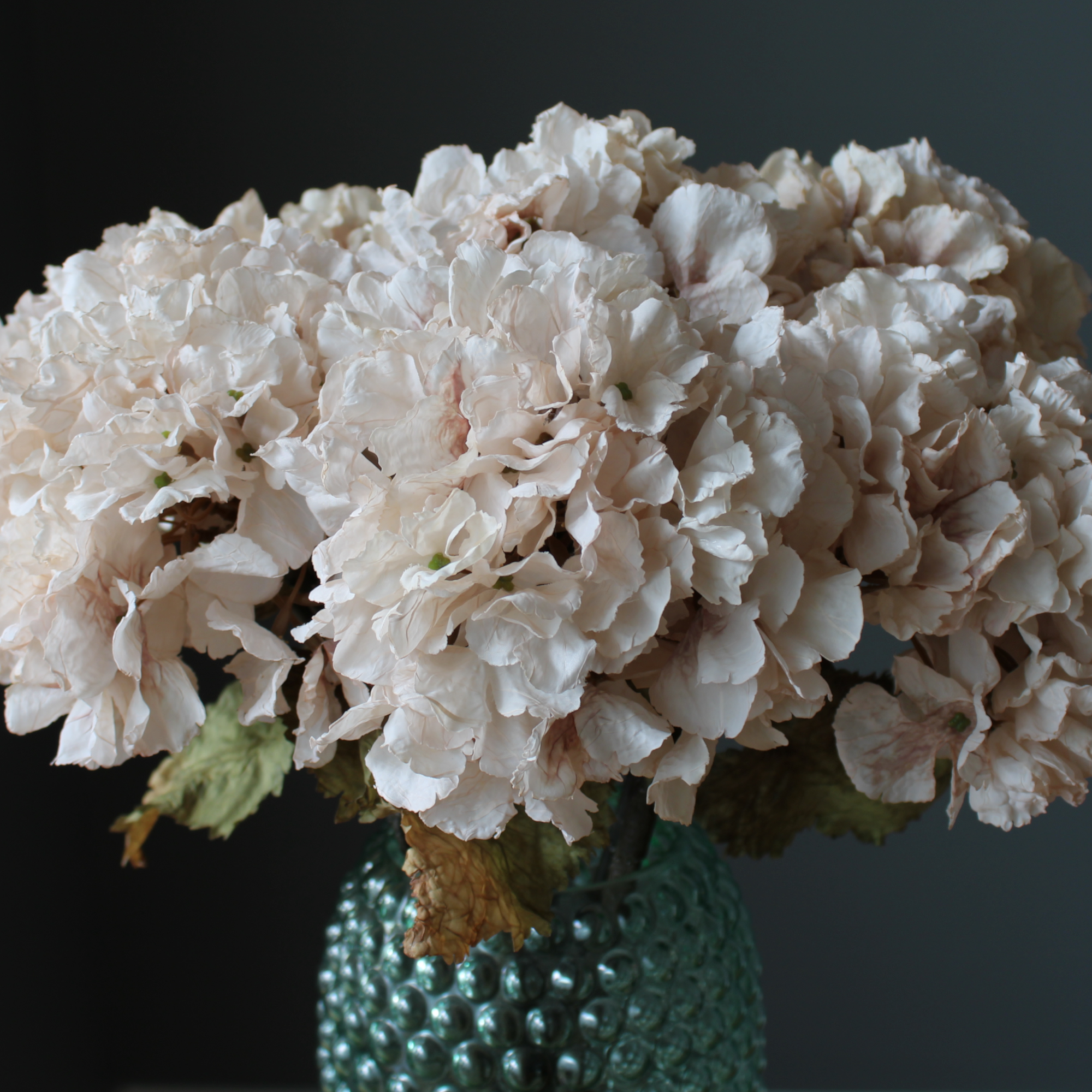 faux real touch hydrangea stems in a decorative vintage green glass vase