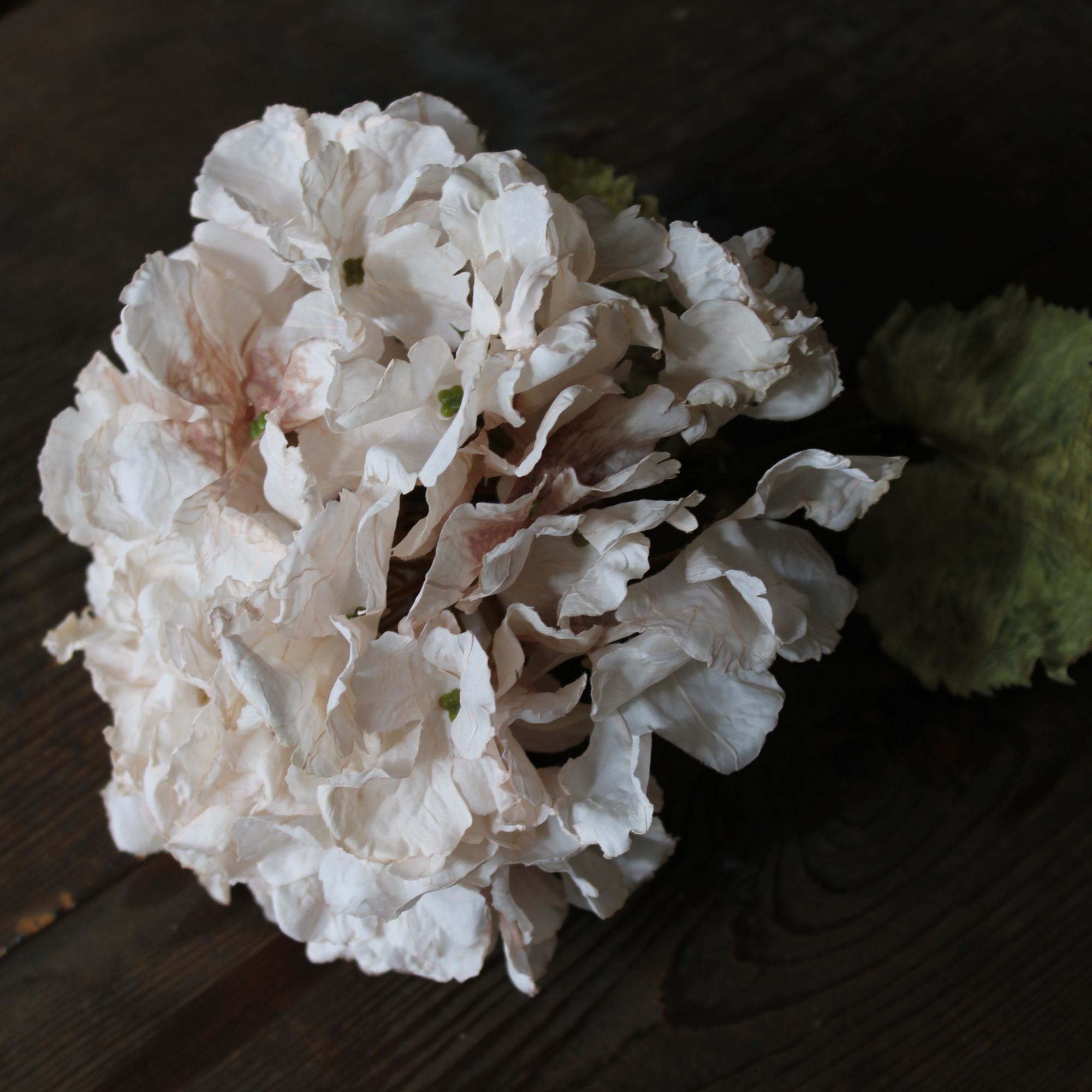cream artificial hydrangea stem on a vintage wood table