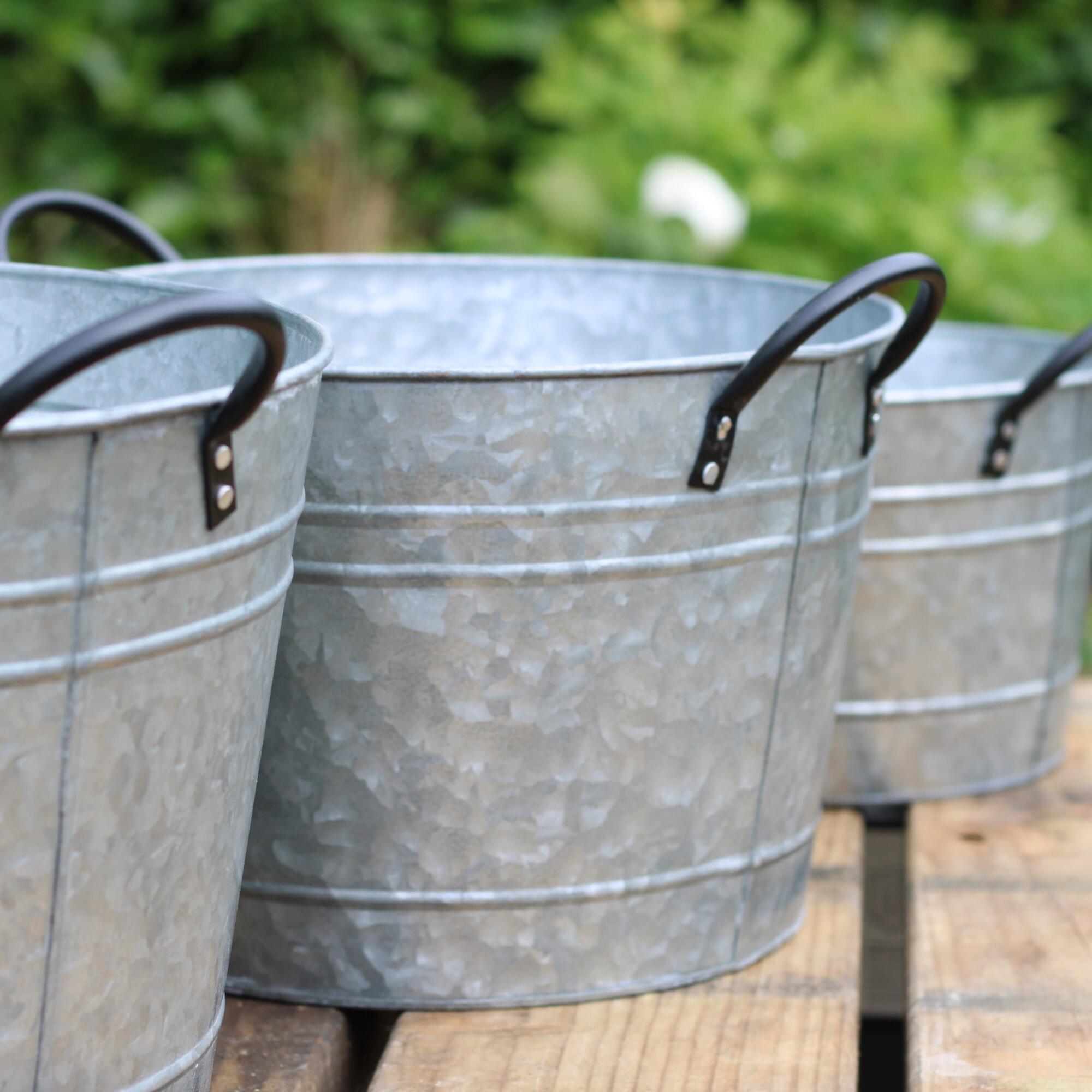 Rustic garden planter tubs with black handles.