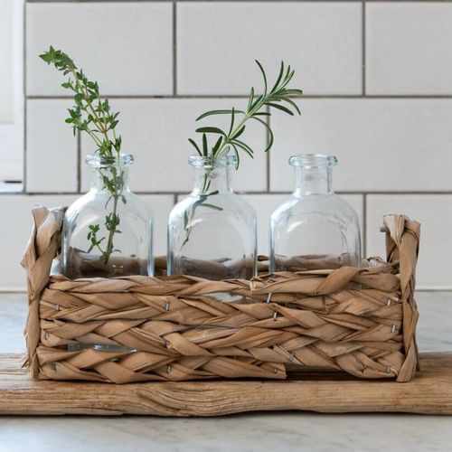 Handcrafted straw basket with three clear bottle vases with herbs
