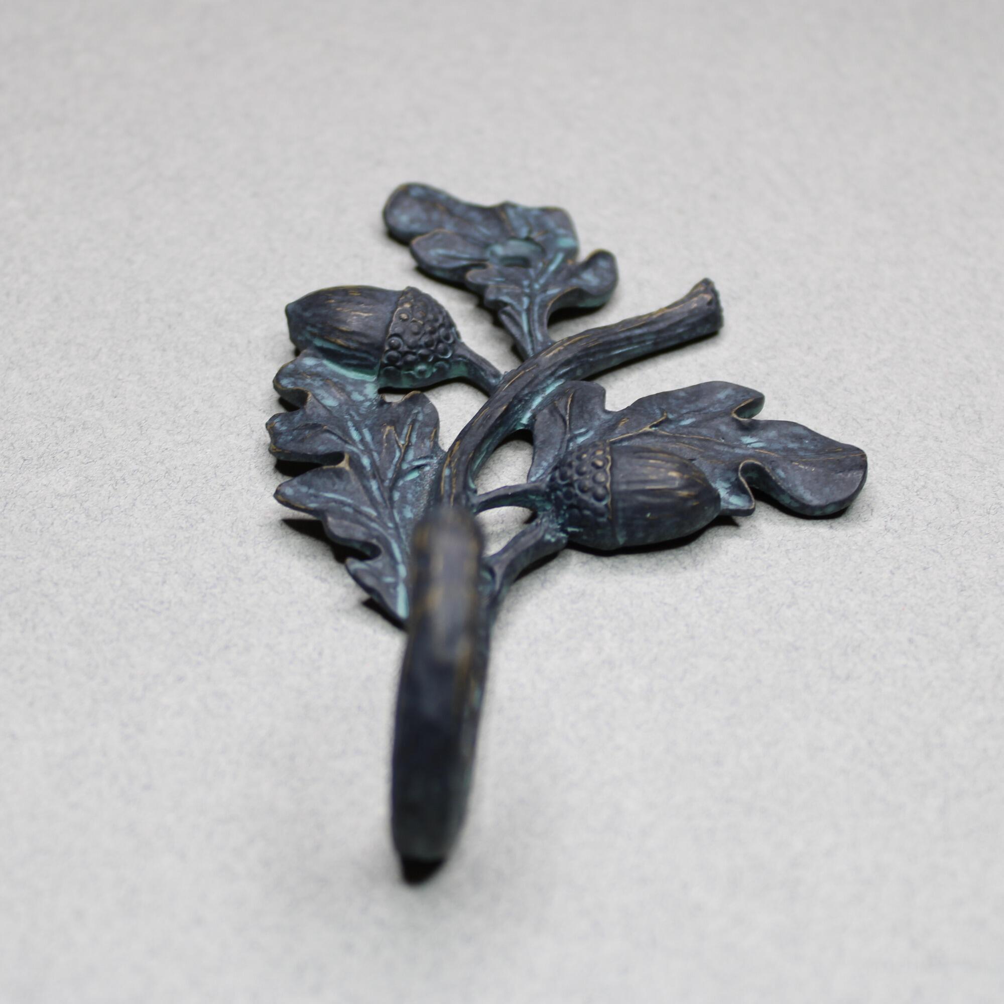Close up of single coat hook featuring textured acorn detail and green bronze finish