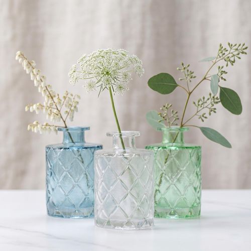 Coloured glass bud vases with single stem flowers