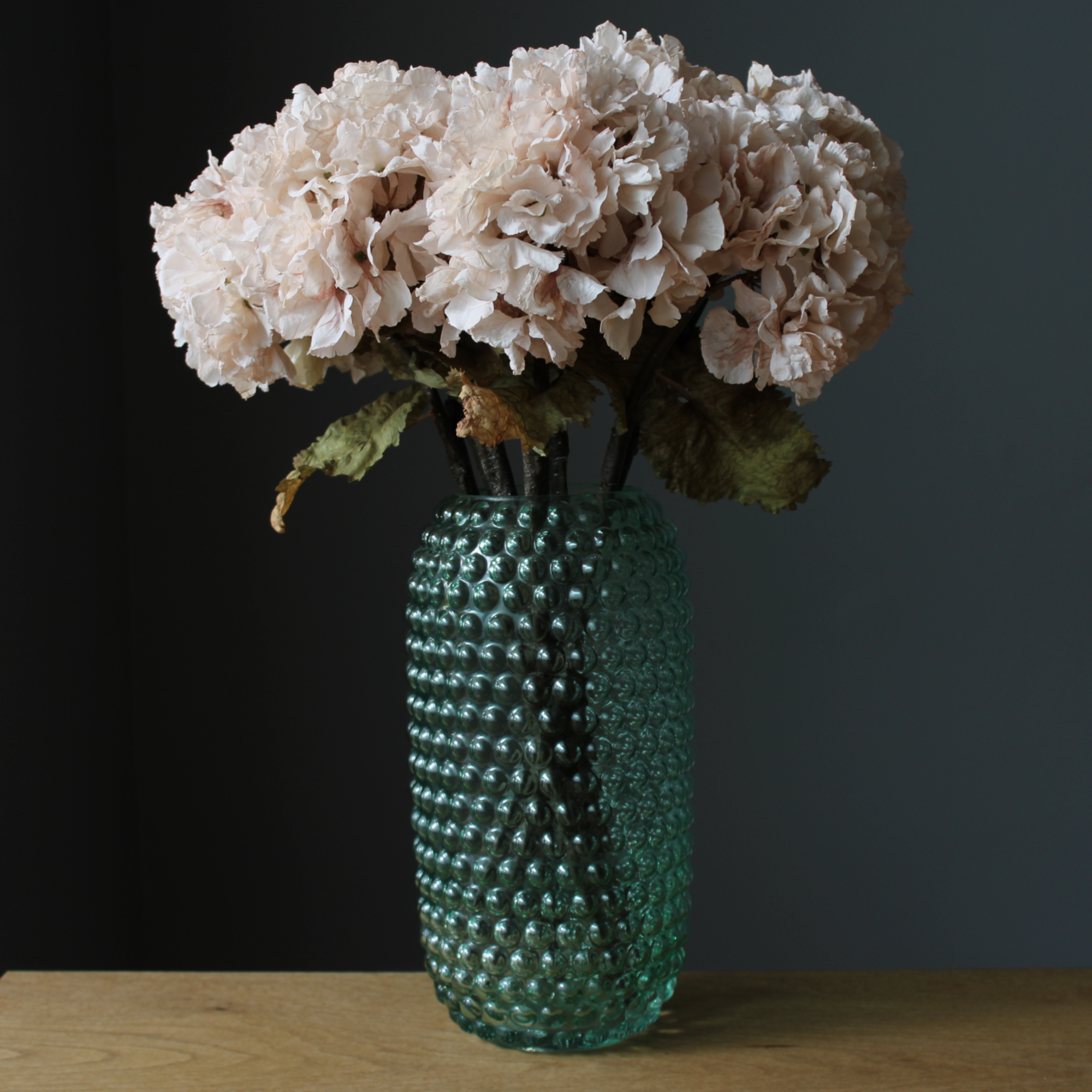 faux real touch hydrangea arrangement in a tall green glass vase