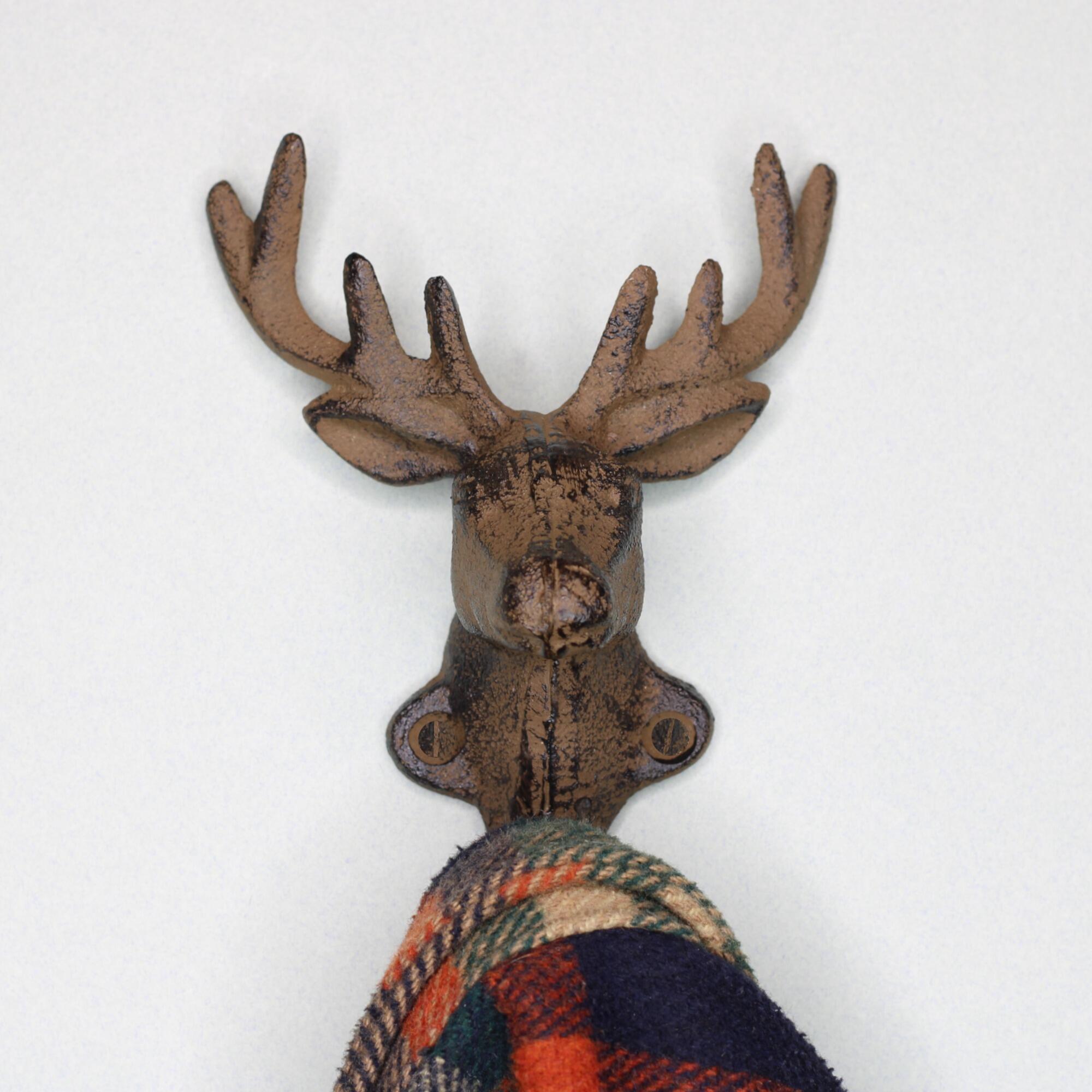 Close-up of a decorative stag head antler hook holding a wool coat, showcasing lodge-style entryway organisation.