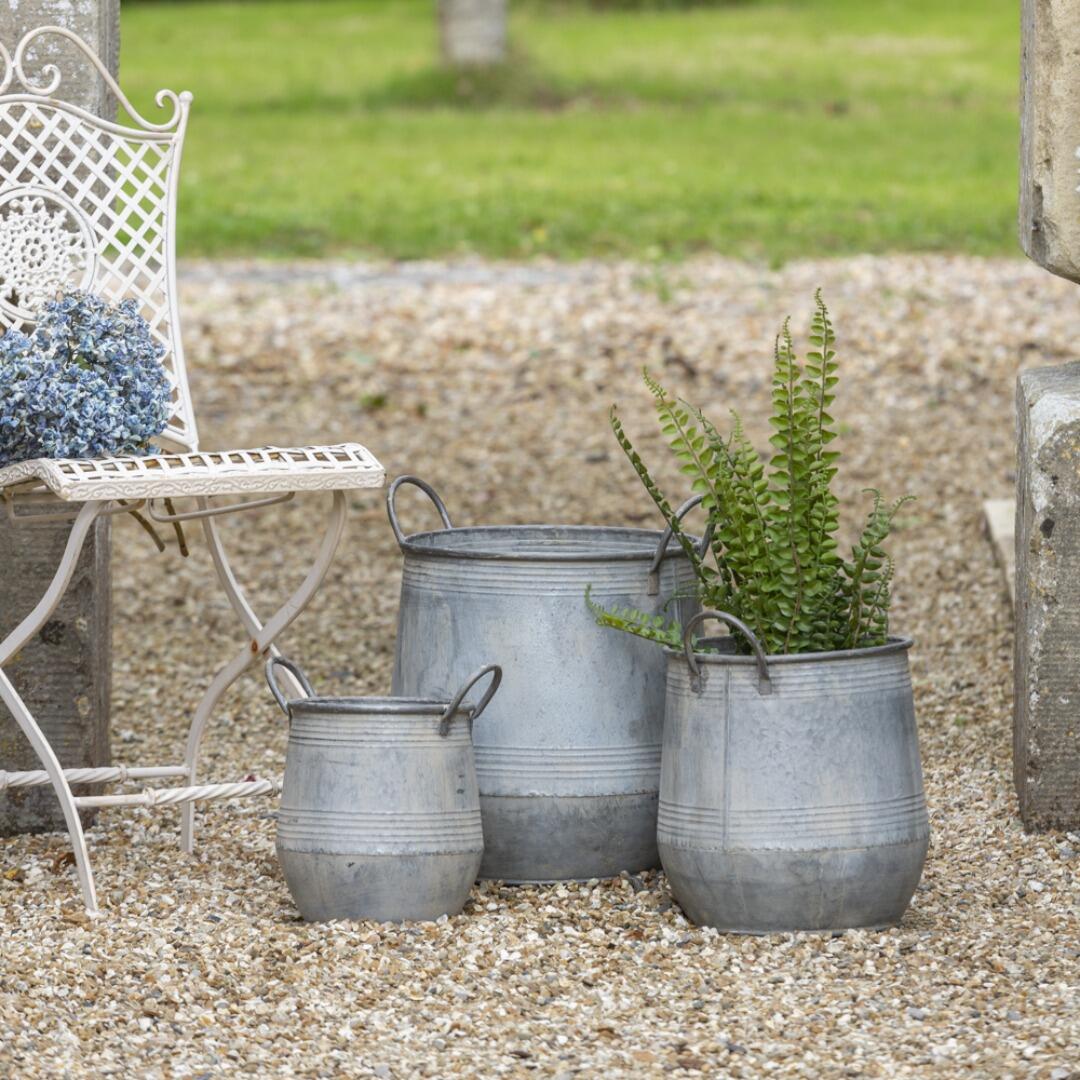 Set of 3 rustic zinc garden planters on gravel