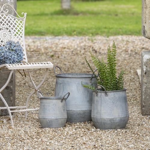 Set of 3 rustic zinc garden planters on gravel