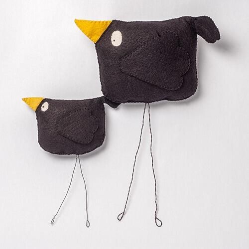 Two 3D padded felt crows named Cuthbert and Charlie with black bodies, yellow beaks, and long, adjustable wire legs.