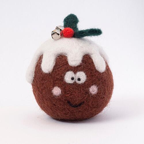 A 3D needle-felted Christmas pudding named Pud with a brown body, white dripping icing, and holly leaves with a red berry and jingle bells on top.