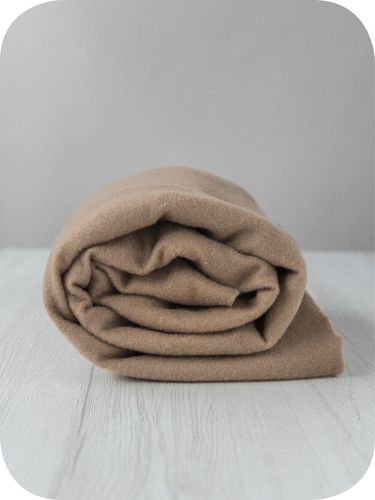 A roll of soft, sandy-brown Earth extra fine merino wool prefelt.