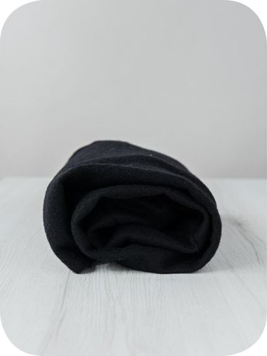 A roll of deep black Dark extra fine merino wool prefelt.