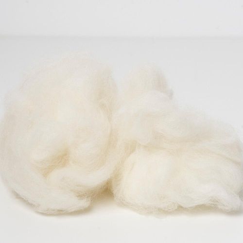 A large, soft mound of white carded core wool, showing the dense, springy texture ideal for needle felting 3D shapes.
