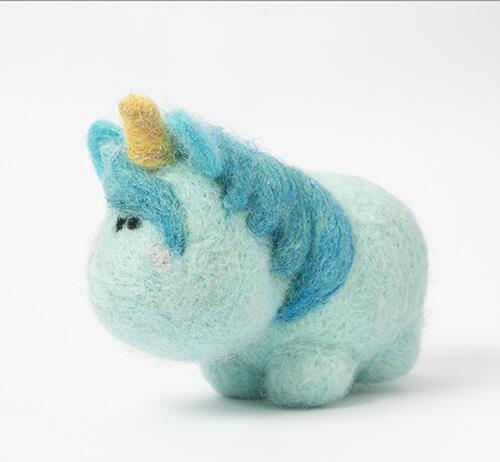 Cute needle-felted turquoise unicorn figurine with a yellow horn and blue mane, from a beginner felting kit.