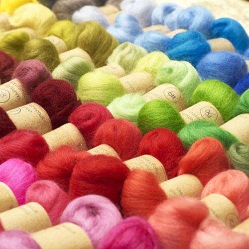 A colourful display of 86 shades of merino wool tops in small bundles, labeled for needle and wet felting