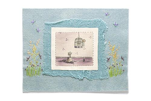 Finished embroidery project featuring a quirky illustration of a black cat named Hector looking up at a birdcage, layered onto pale blue felt with embroidered floral and dragonfly details.