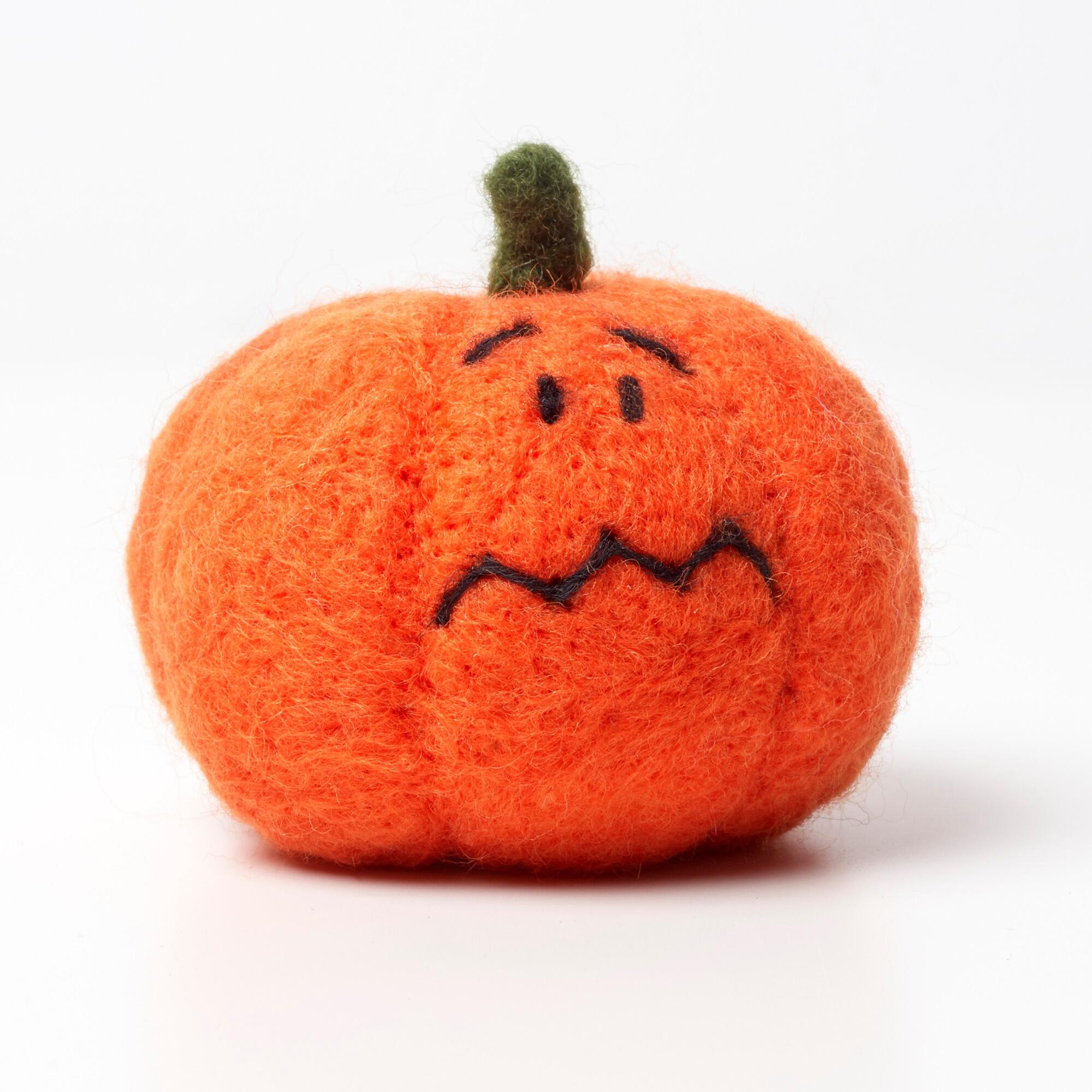 A 3D needle-felted bright orange pumpkin with a green stem and a worried zigzag stitched mouth.