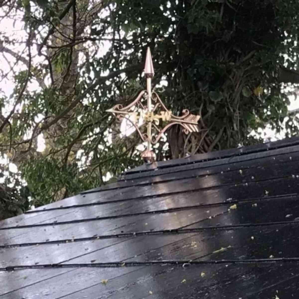 Copper Victorian arrow weathervane installed on a log cabin with slate roof showing the design in situ
