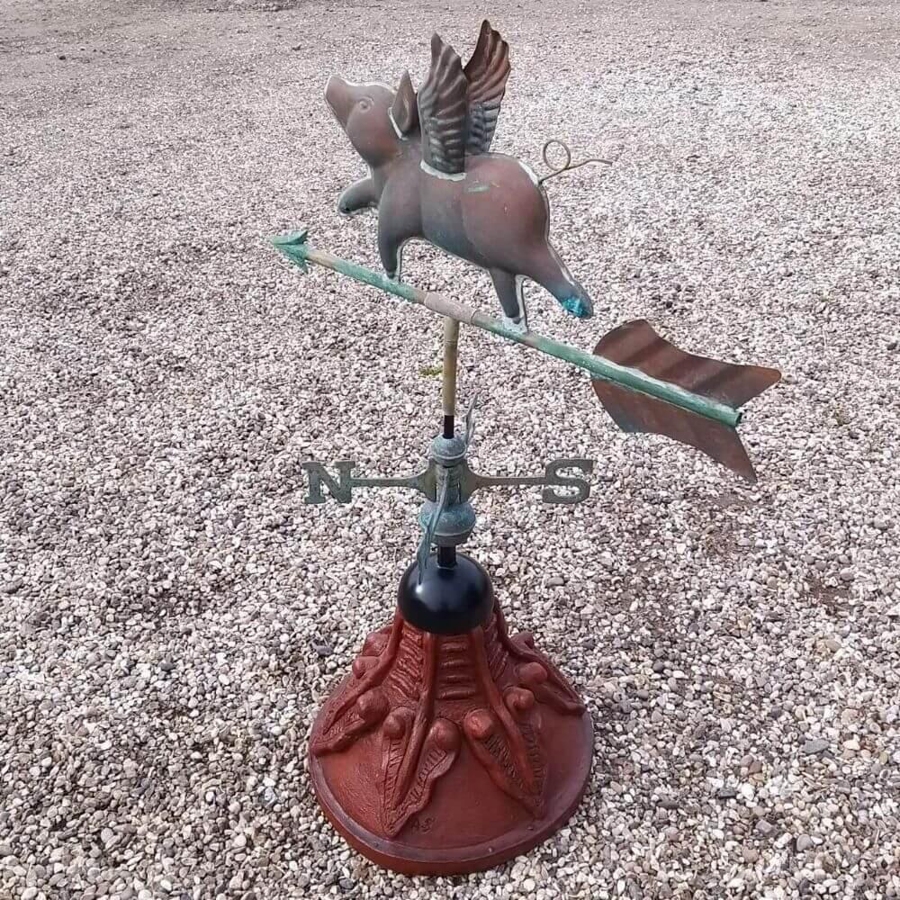 Flying pig weathervane fixed on a round ridge tile cap