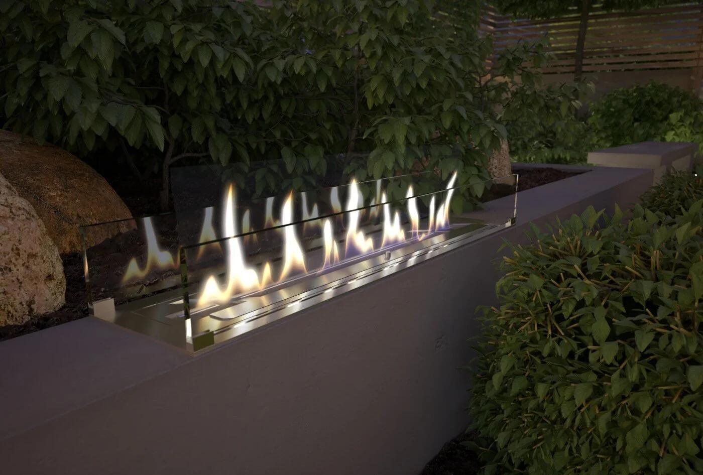 Outdoor built-in burner flames along a garden wall planter at night