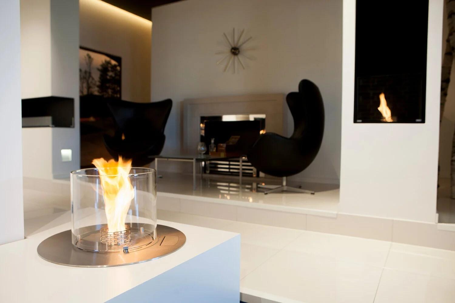Denver F6 Round burner recessed into a white surface with a flame inside a glass cylinder