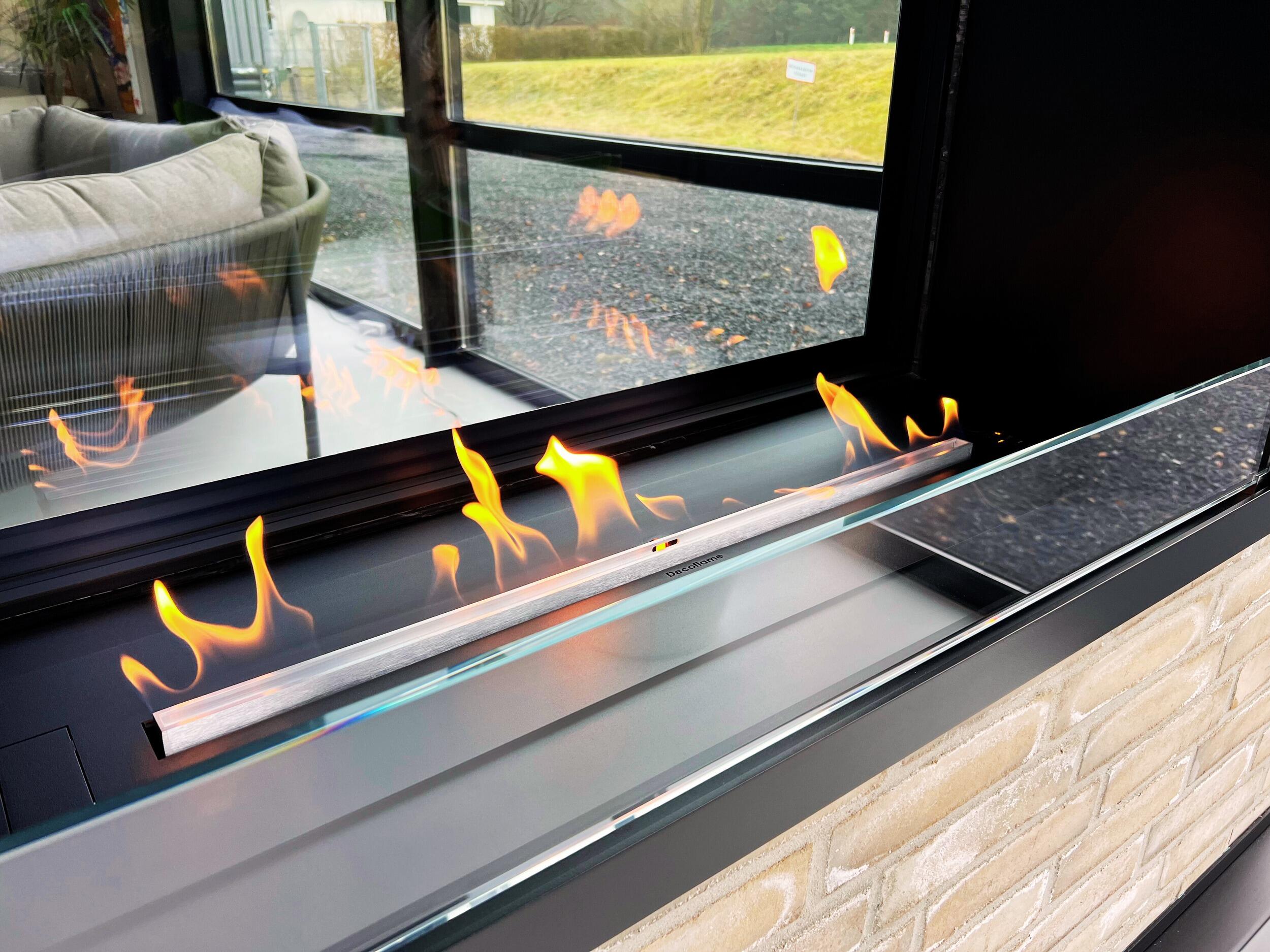 Montreal Clear burner flames with the garden visible through the glass