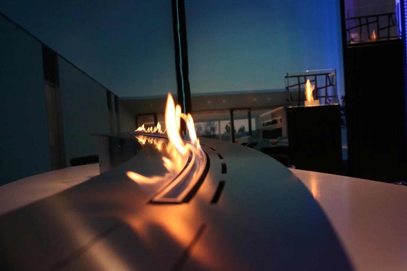 Denver Curved F6 burner lit at dusk in a curved stainless steel surround