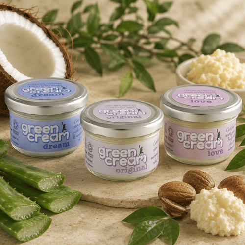 Three Green Woman Green Cream organic moisturisers (Original, Dream and Love) displayed together on a natural stone surface, surrounded by fresh aloe vera, coconut, shea butter and botanical leaves, highlighting the plant-based ingredients and certified organic skincare range.