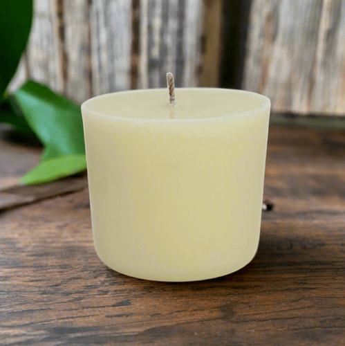White essential oil candle refill on a wooden surface with a blurred natural background