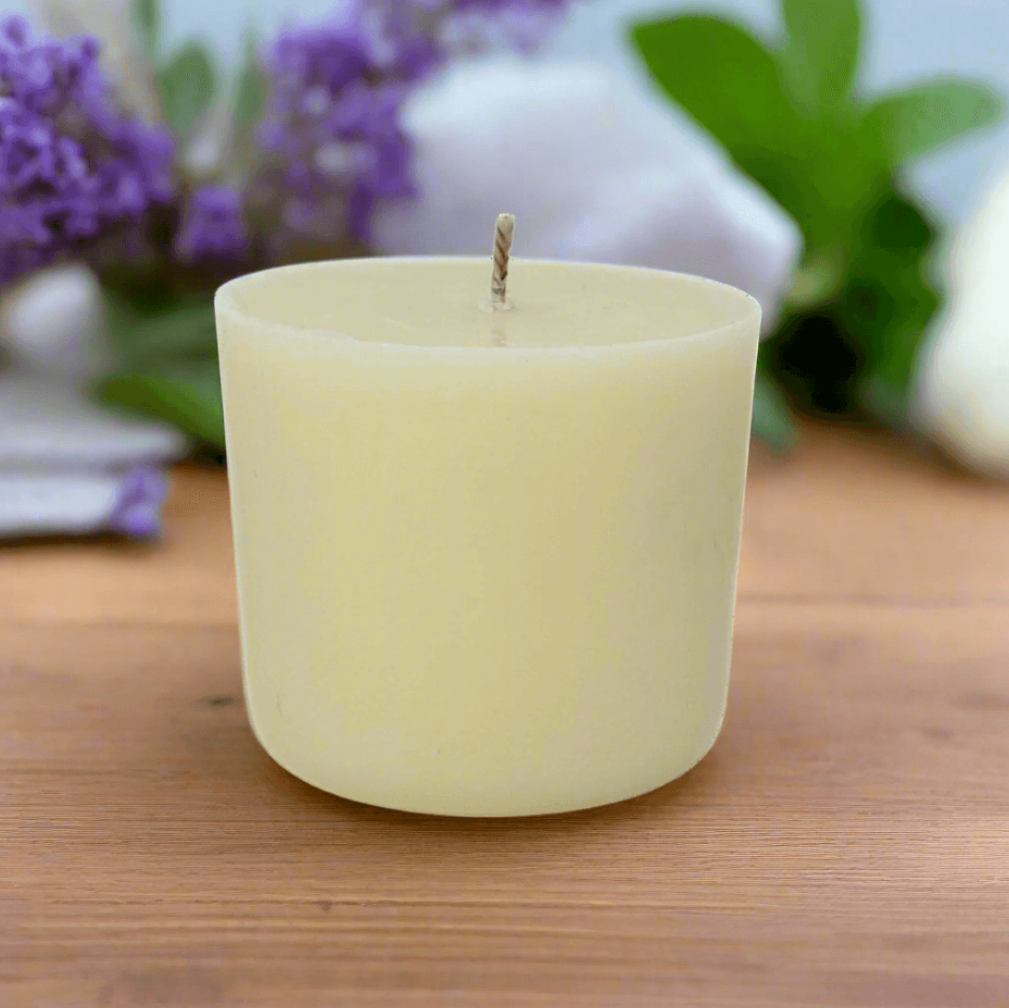 White candle refill on a wooden surface with blurred lavender flowers in the background