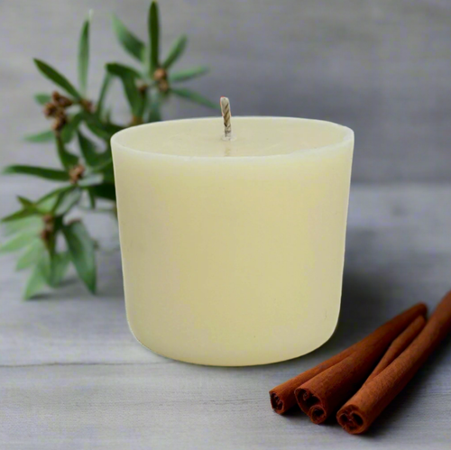 White refill candle with cinnamon sticks, lavender and Ylang Ylang on a light surface