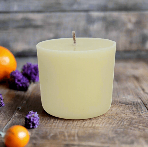White candle refill on a wooden surface with oranges and lavender flowers