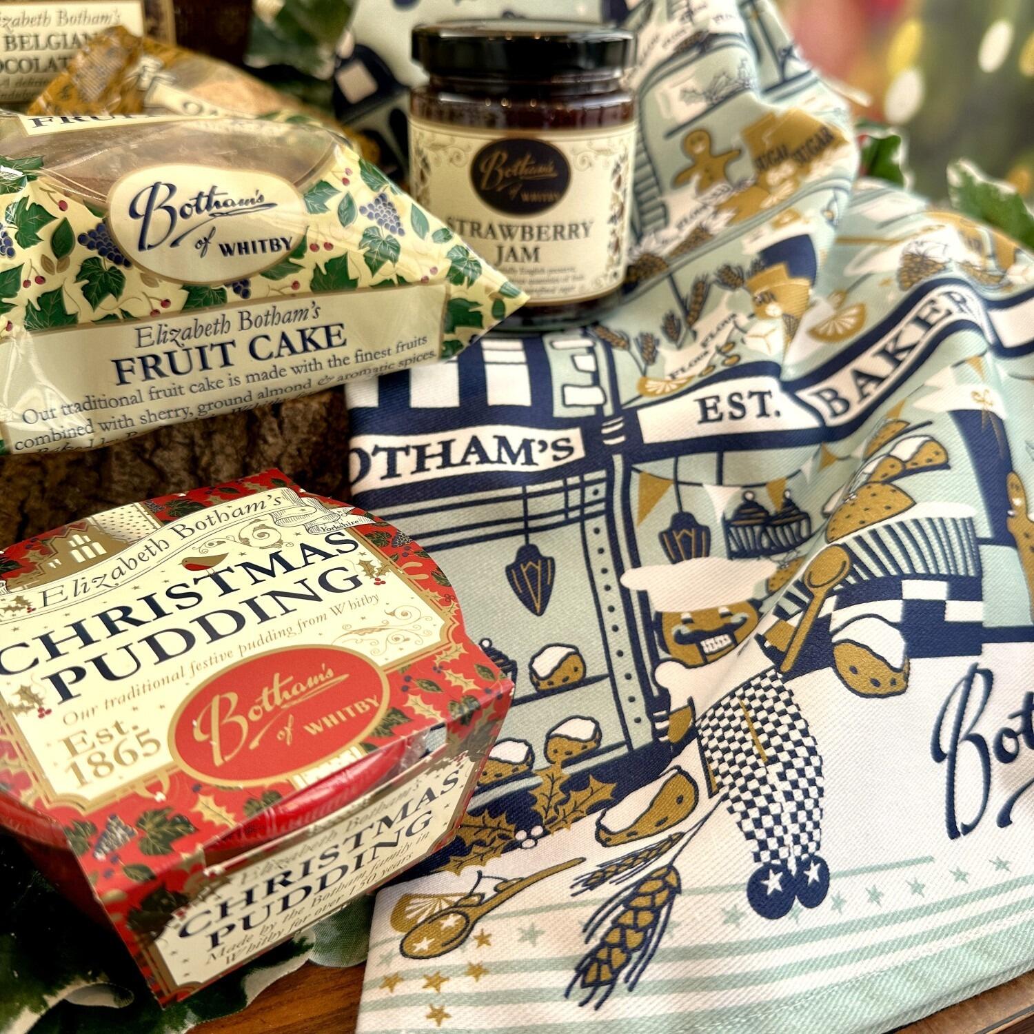 ‘Season’s Greetings Gift Box’ festive food hamper is a delightful Christmas hamper containing delicious bakes from Botham's of Whitby bakery, with a focus on Elizabeth Botham’s Fruit Cake, Christmas Pudding, and jar of Strawberry Jam. Add some Botham’s magic to washing up with the festive tea towel by family designer, Anita Marshall, and this year’s design depicts a magical interpretation of a Botham’s Nutcracker scene. This is an exquisite Yorkshire Christmas food hamper by post from Botham’s iconic Whitby bakery.