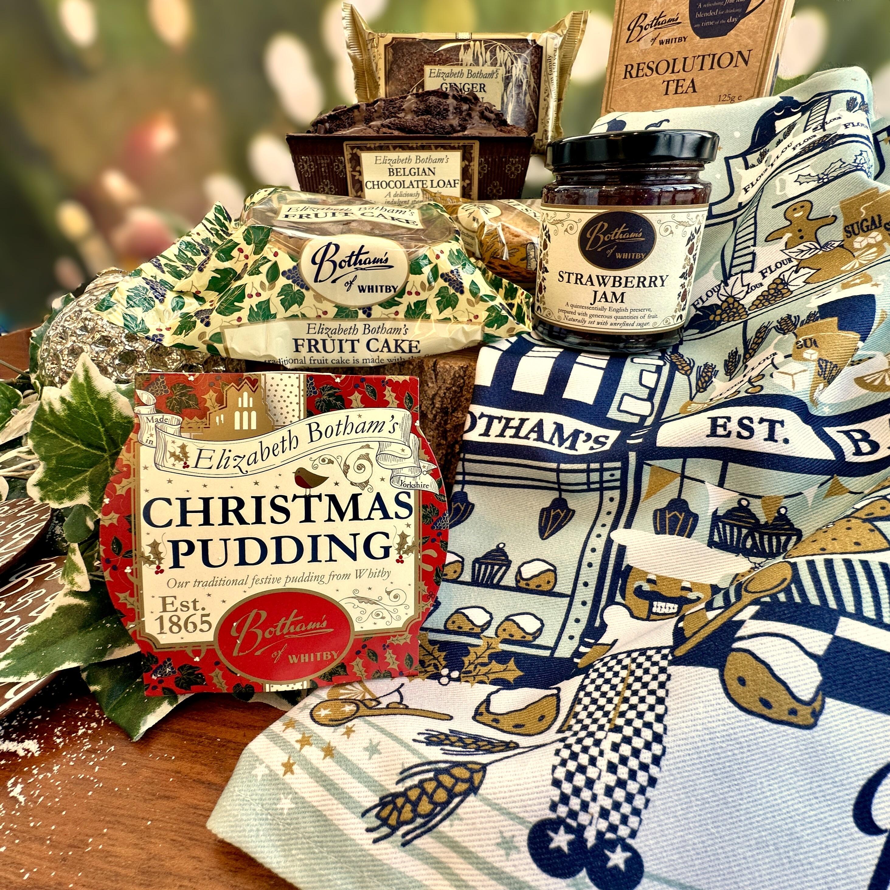 ‘Season’s Greetings Gift Box’ festive food hamper is a delightful hamper containing delicious bakes from Botham's of Whitby bakery, such as Ginger Parkin, Belgian Chocolate Loaf, Elizabeth Botham Fruit Cake, Christmas Pudding and a selection of Twin Pack Biscuits. Add some Botham’s magic to washing up with the festive tea towel by family designer, Anita Marshall, and this year’s design depicts a magical interpretation of a Botham’s Nutcracker scene. Strawberry Jam and house blend Resolution Tea complete this exquisite Yorkshire Christmas food hamper by post from Botham’s iconic Whitby bakery.