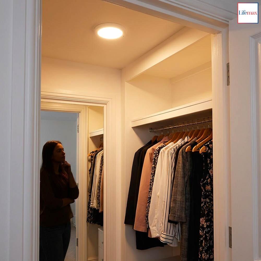 A young lady looking at the her clothes in a cupboard illuminated by the Lifemax Rechargeable Motion Ceiling Light