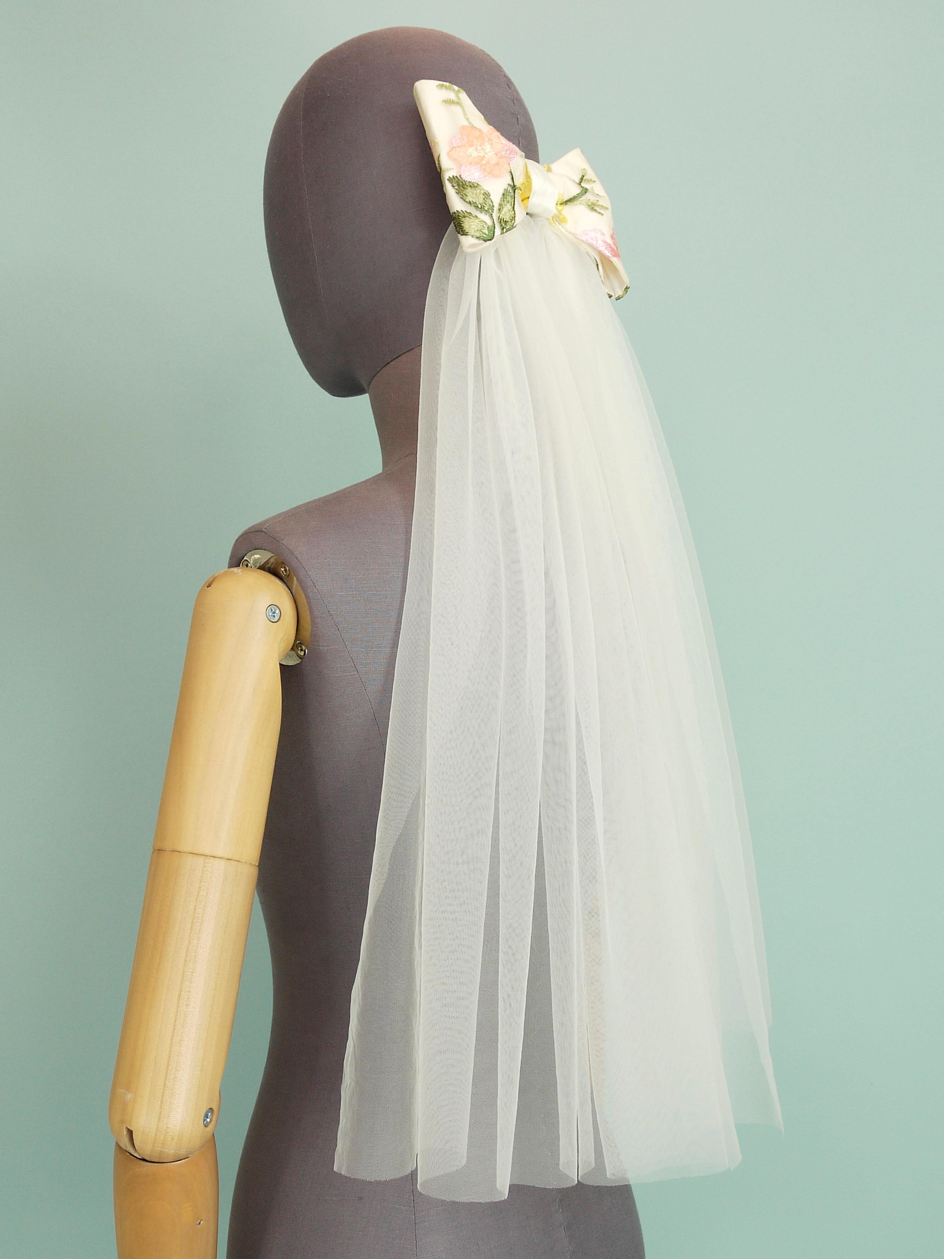 A bridal bow hair accessory made in silk and floral lace with soft tulle tails